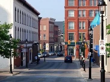 A quiet urban street lined with red brick and white buildings under clear skies.