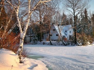 A snowy winter scene with a white house surrounded by bare trees.