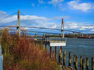 A large suspension bridge over a river on a sunny day.