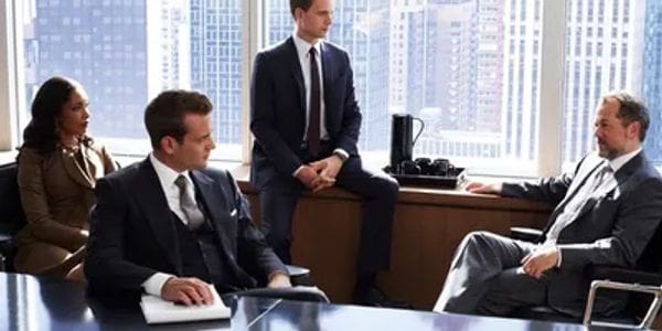 Three businessmen in suits discussing in a modern office.