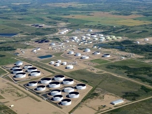 Aerial view of an oil refinery with multiple storage tanks and pipelines.