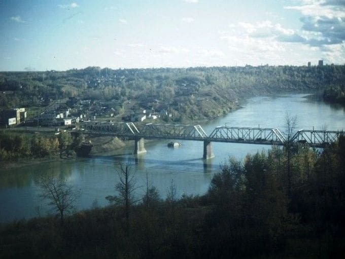 A scenic view of a river with a bridge and forested hills.