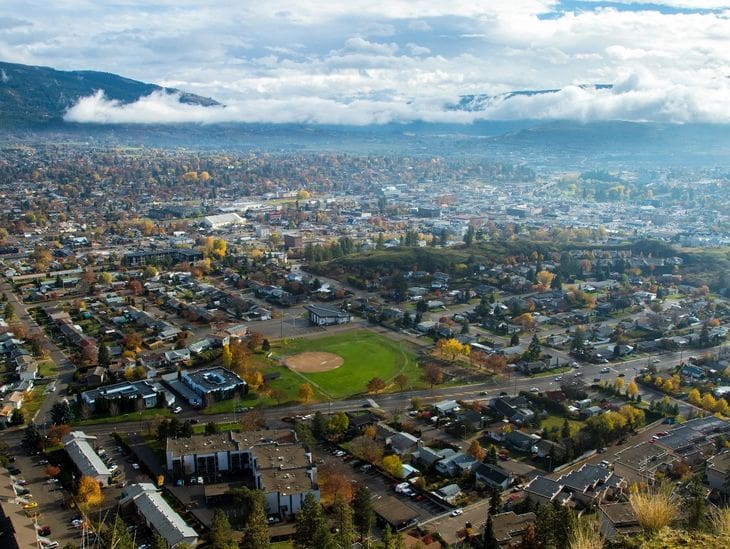Aerial view of a city with a central green park under a cloudy sky.
