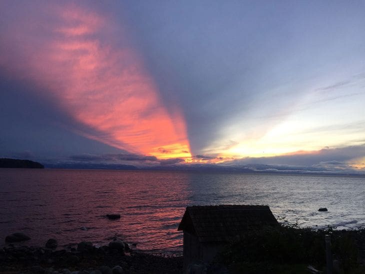 Sunset casting vibrant colors and shadows over a calm sea.
