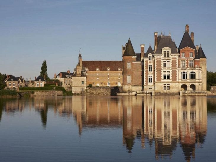A historic castle by a calm river under a clear sky.