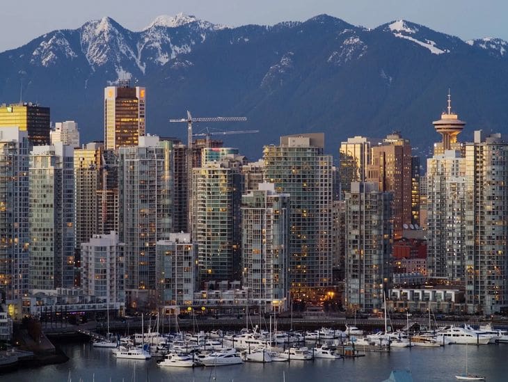City skyline with marina and mountains at dusk.