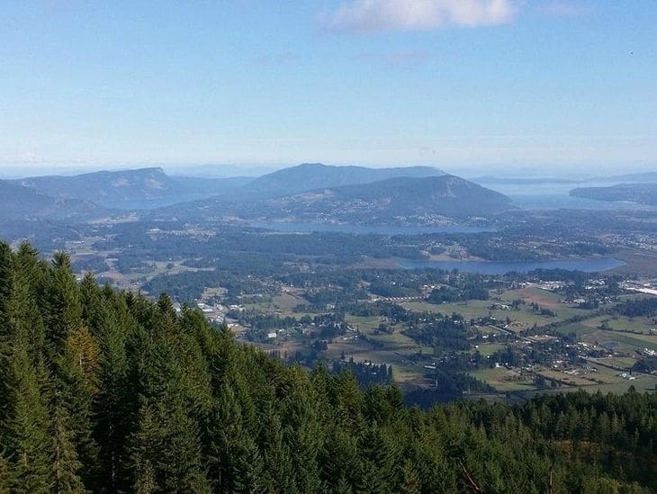 Scenic mountain view overlooking a valley with forests and distant hills.
