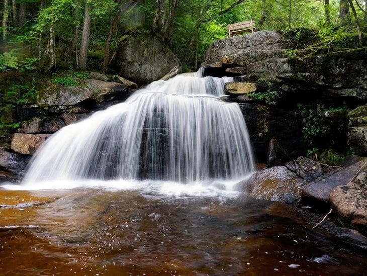 A serene waterfall cascading over rocks into a calm pool below.