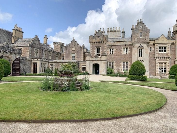 A historic castle with manicured gardens under a cloudy sky.