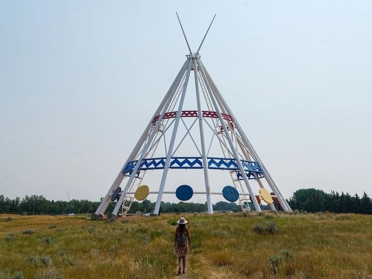 Large teepee-like structure with geometric designs in an open field.