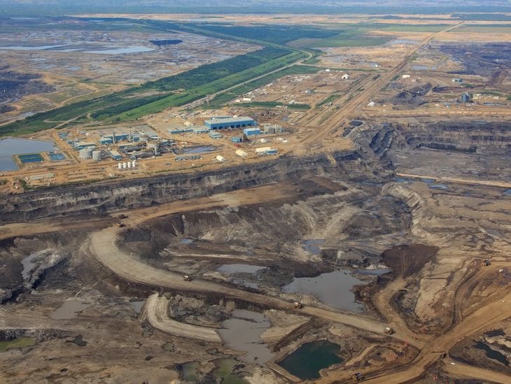 A large open-pit mining operation with heavy machinery and disturbed earth.