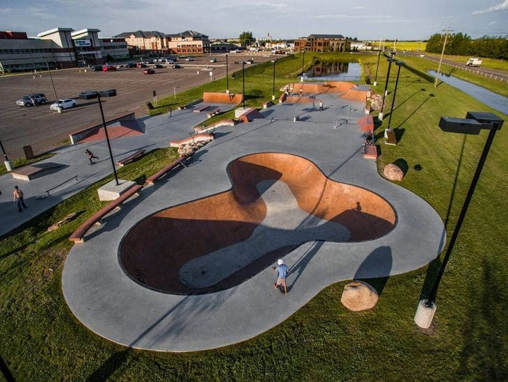 Aerial view of a skateboard park with ramps and bowls under sunlight.
