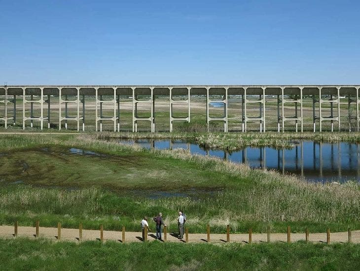 A large concrete bridge over water with people walking nearby.