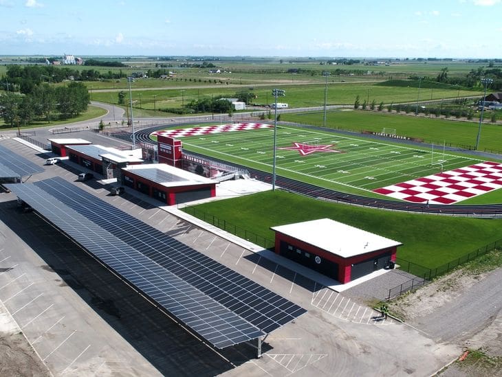A bright go-kart track with grandstands and pit buildings under clear skies.