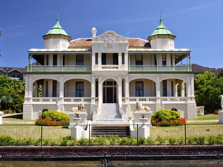 Elegant historic mansion with twin green turrets and a grand staircase.