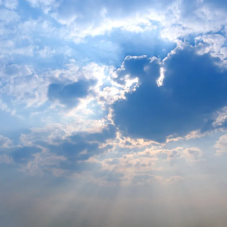 Sun rays breaking through blue cloudy sky